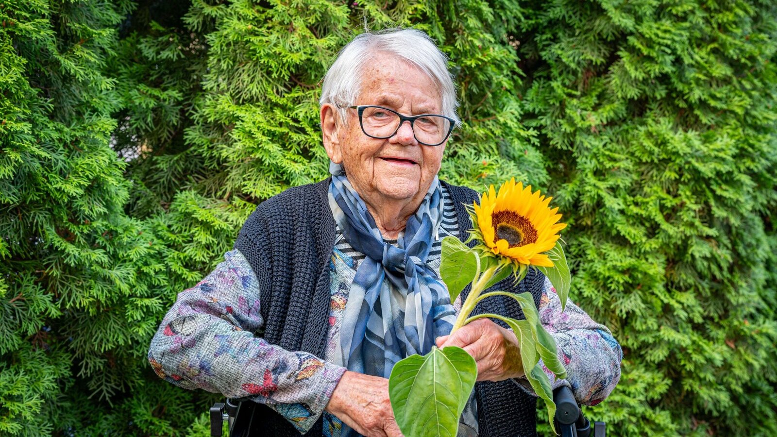 Bewohnerin mit Sonnenblume im Garten